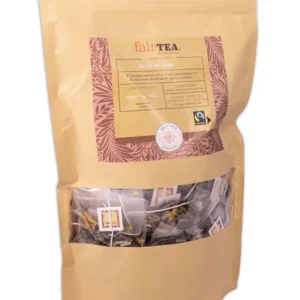 Gylden papirpakke med FairTea la vie en rose-te, med et klart vindu som avslører teposer inni, utsmykket med etiketter og en fair trade-logo.