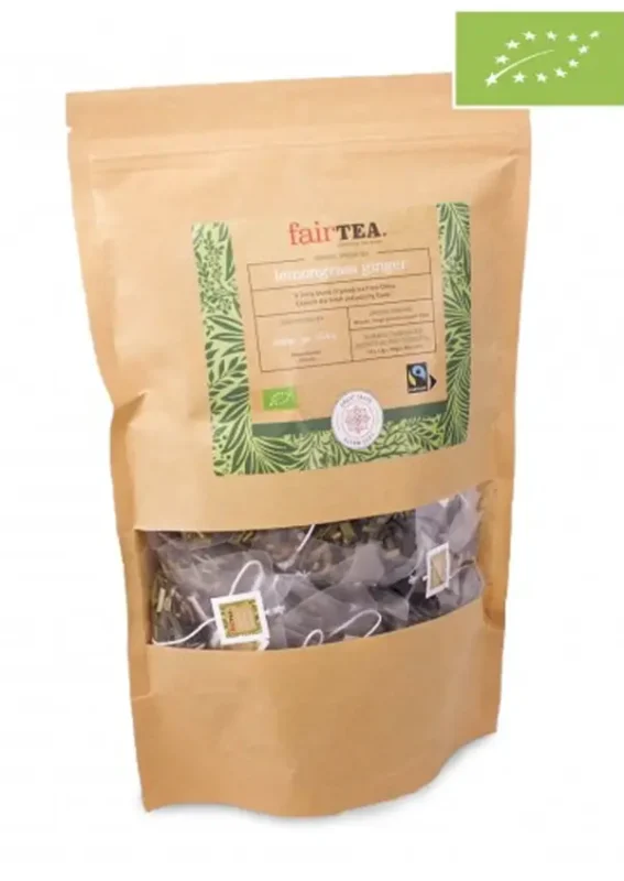 En brun papirpose med "FairTea Lemon Ginger" sitrongresste med synlige teposer inni, sertifisert økologisk og rettferdig handel, isolert på en hvit bakgrunn.