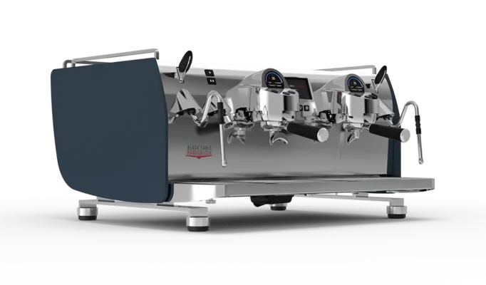 Denne kommersielle espressomaskinen er en Nuova Simonelli Oscar kaffemaskin, og har to gruppehoder, digitale displayer og portfiltre, alt i rustfritt stål med elegante mørkeblå sidepaneler.