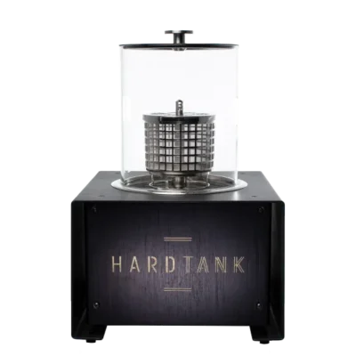 Bildet viser en Hard Tank-enhet, med en mytisk sylindrisk metallkomponent innkapslet i en glassbeholder på toppen av en elegant svart base merket "HARD TANK.