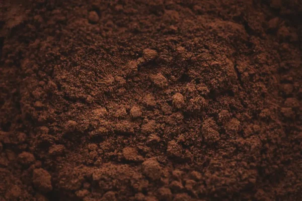 Nærbilde av fyldig, mørkebrun kaffegrut med et strukturert, granulært utseende, ideelt for gjenbruk av kaffegrut.