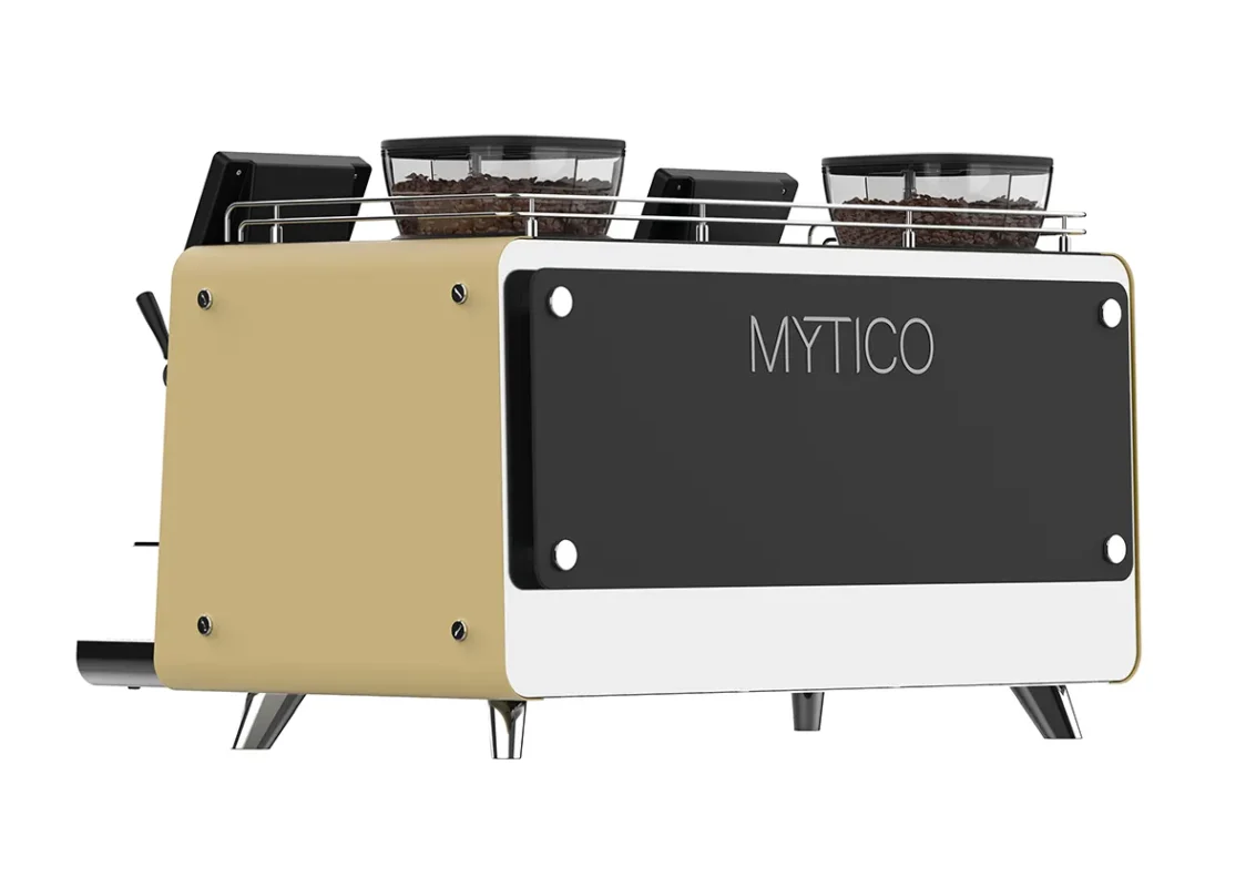 En moderne espressomaskin med beige og svart eksteriør, merket "MYTICO", med to kaffebønnebeholdere på toppen.