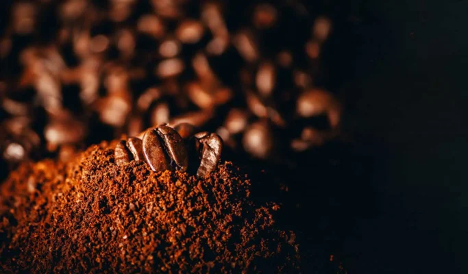 Kaffebønner på toppen av malt kaffe med en mørk, uskarp bakgrunn med en Bravilor Bonamat Esprecious 22 kaffemaskin.
